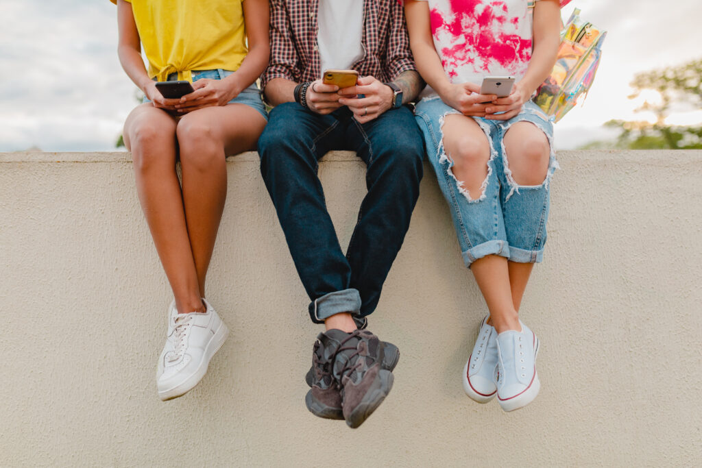 legs sneakers young company friends sitting park using smartphones