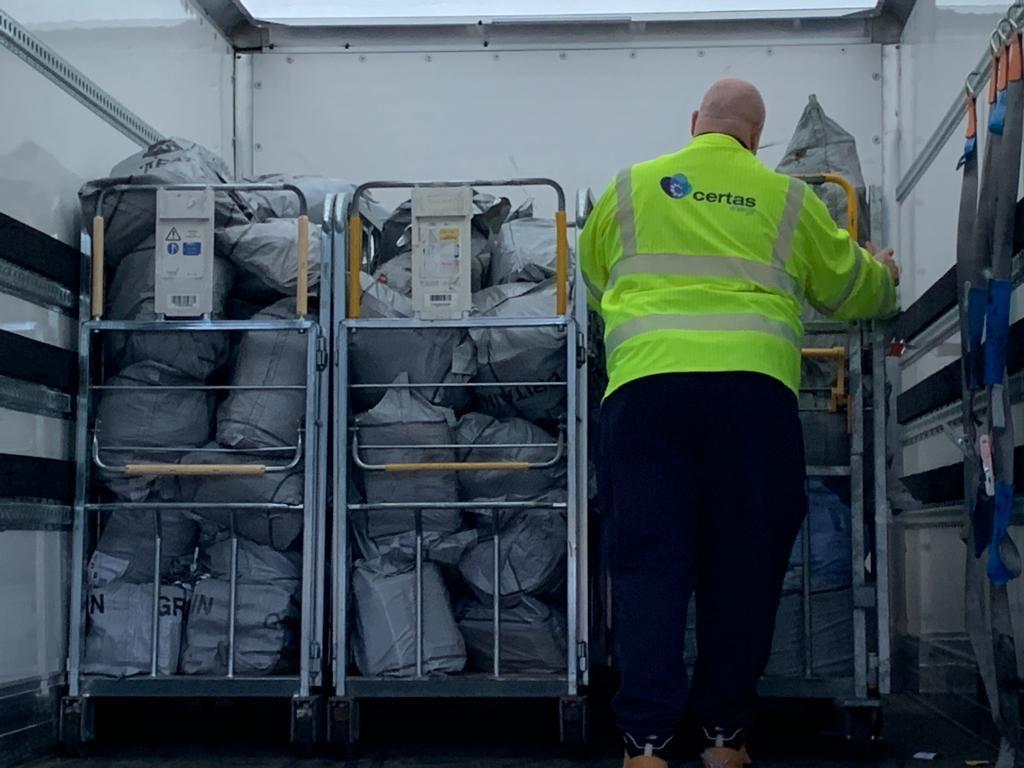 Courier loading full collection cages of parcels